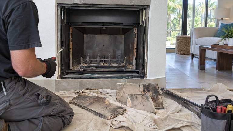 A factory-built fireplace with its cracked refractory panels removed and set on a drop cloth.